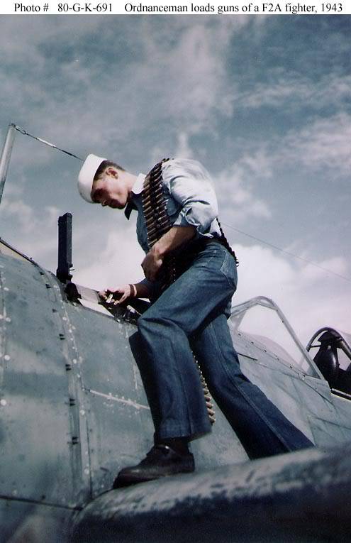 Un miembro del equipo de tierra recarga la munición de un caza F2A, 1943