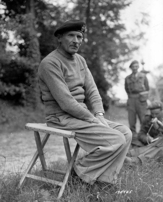 Retrato de Montgomery sentado en un taburete plegable con sus ayudantes a la derecha. Normandia, verano de 1944