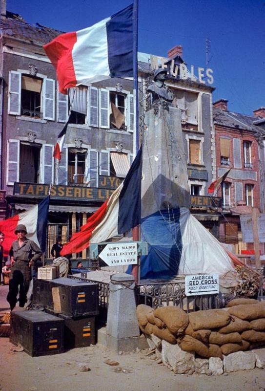 Tropas estadounidenses junto al monumento de la I Guerra Mundial adornado con banderas francesas después de que la ciudad fuera liberada de las fuerzas de ocupación alemanas, verano 1944