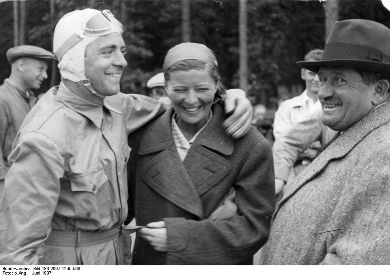 El nuevo ganador del récord de velocidad le brilla la cara cuando su esposa, Elli Beinhorn-Rosemeyer y el diseñador de Auto Union, el Dr. Porsche, le felicitan por su victoria. 16 de junio de 1937