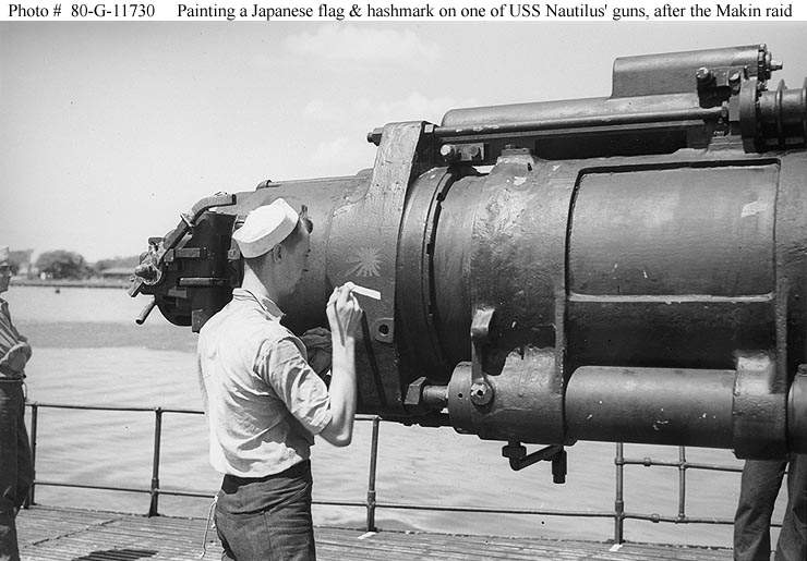 Un miembro de la tripulación pinta una bandera japonesa y una marca en uno de los cañones del Nautilus SS-168, representando a los dos buques enemigos que hundió con disparos durante la incursión de Makin. Fotografiado en Pearl Harbor, Hawai, el 25 Agosto de 1942