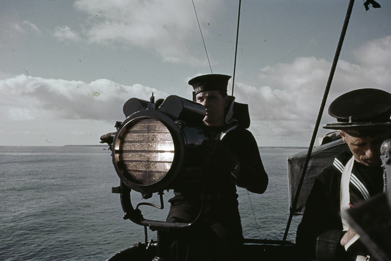 Un comunicador opera una lámpara Aldis a bordo de un buque de guerra británico en 1942