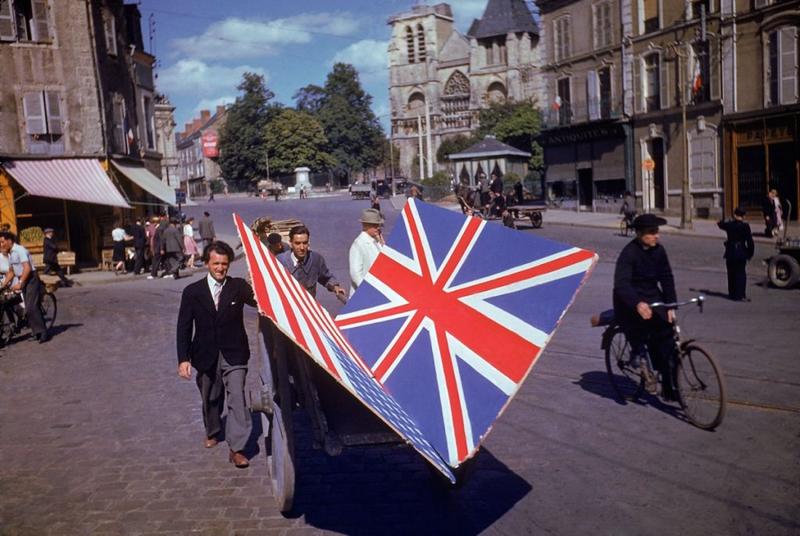 Dos franceses transportan dos banderas, británica y estadounidense, para ser usadas en un desfile, verano de 1944