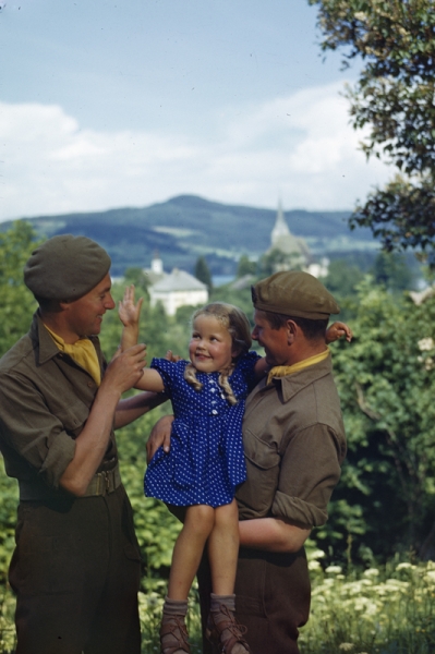 Dos soldados de la Policía Militar Real con Anna, una niña austriaca de cuatro años de edad con cuya familia se alojaban los hombres, en la zona ocupada Klagenfurt de Austria, mayo de 1945