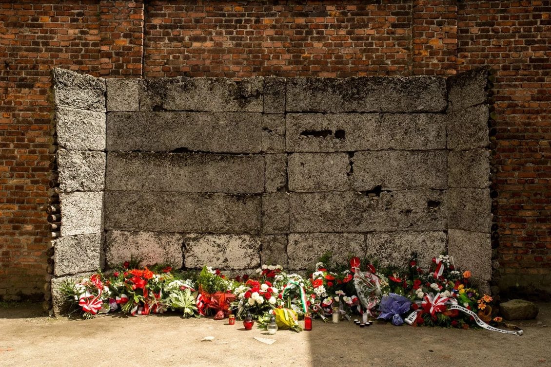 Una pila de flores debajo de la pared de la muerte dentro del Memorial y Museo de Auschwitz-Birkenau. Ken Cedeno. Getty Images