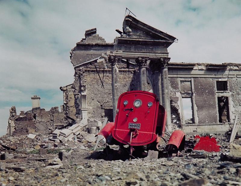 Vista de las ruinas del Palacio de Justicia de la ciudad de St. Lo, Francia, verano de 1944. La pieza roja de metal en primer plano es lo que queda de un camión de bomberos